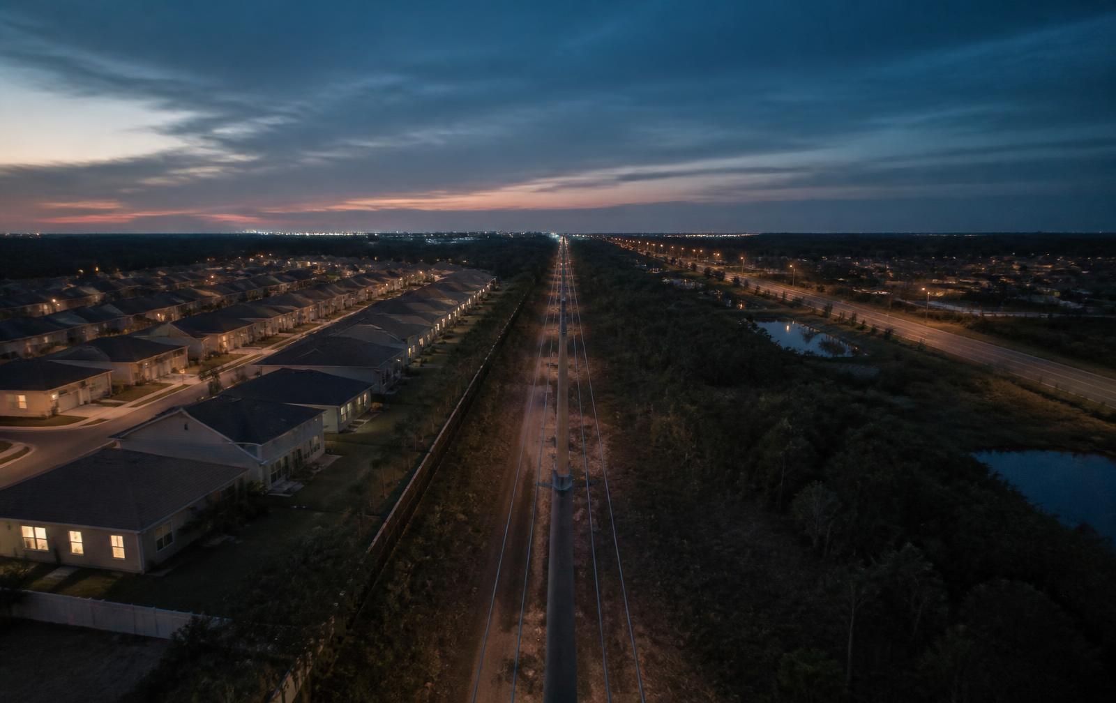 Aerial telecom corridor at twilight cutting through Florida suburban development
